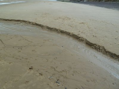 Le sable creusé par l'eau de façon différente des deux côtés. 